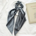 Close-up of a grey velvet scrunchie with ribbons on a white tray and vintage book - Grey Velvet Streamer