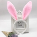 White plush bunny ear headband with pink inner lining next to flowers and photo frame - White and Pink Rabbit
