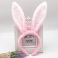 Detail of pink plush rabbit ears headband with soft texture next to a white photo frame - Pink and White Rabbit