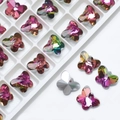 Macro shot of 14mm pink and purple butterfly crystal pendants on white grid tray - Rose Red