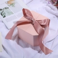 Octagonal pink gift box featuring a decorative pink ribbon bow on a soft fabric background - Champagne Pink; String Lights (1 Meter Long)