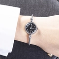 Women's quartz cuff watch featuring a silver cable band and black round dial on wrist - Arabic Numerals Silver Band Black Dial