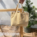 Detail of yellow and white gingham cotton linen tote bag held by a model in a natural setting - Yellow
