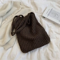 Bolso tote de hombro tejido marrón oscuro con textura suave sobre sábana blanca - café