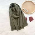 Close-up of olive green cashmere scarf with fine tassels on white fabric background - Creamy Green