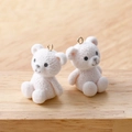 Close-up of white plush teddy bear charms with golden loops for DIY jewelry making - White