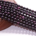 Polished purple tiger eye stone beads on a wooden base for DIY jewelry making - Space Tiger Eye