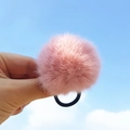 Chouchou en peluche rose avec pompon doux et élastique noir sur fond de ciel bleu - Rose