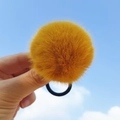 Chouchou à pompon en peluche jaune gingembre avec élastique sur fond de ciel bleu - Jaune gingembre