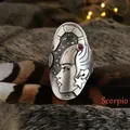 Macro detail of vintage silver Scorpio ring with female profile and red gemstone inlay - Scorpio