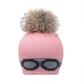 Détail d'un bonnet en tricot rose avec pompon en fourrure et motif de lunettes - Rose-Pompon Fourrure Raton Laveur