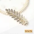 Detail of a golden alloy leaf spring clip with intricate veins on a pearl lace background - Gold Leaf Spring Clip