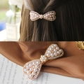 Elegante gouden strik haarklem met parels en strass op model en close-up weergave - Parel bloem strik veerclip