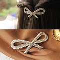 Golden alloy bow hair clip with white pearls and rhinestones shown on hair and fabric - Gold Graceful Bow Spring Clip