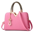 Pink geometric embossed handbag with woven handle and pearl charm on white background - Pink