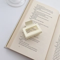 Elegant beige square hair claw clip placed on vintage book page for a minimalist aesthetic - Creamy White