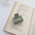Light green medium square matte hair claw clip placed on open book pages for styling - Green