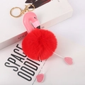 Detailed close-up of flamingo pom-pom keychain with red fur and pink leather on a book - Bright Red - Gold Lobster Clasp