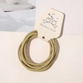 Detail of high-elasticity golden hair ties with metallic woven texture on display card - Yellow