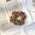 Single brown velvet scrunchie accessory displayed on a stylish vintage newspaper backdrop - Coffee