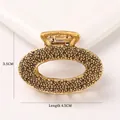 Detailed macro view of gold alloy hair claw with textured finish and spring mechanism - Oval - Antique Gold