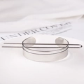 Detail shot of a polished silver metal bun cuff with a U-shaped hairpin on a white plate - Minimalist Hoop / Silver