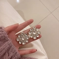 Macro shot of sparkling crystal flower earrings held by hand to show fine details - Silver Flower Style With Sterling Silver Pin
