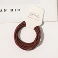 Detail of high-elastic coffee brown hair ties on a display card with bow accents - Rust