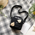 Close-up of cute black canvas crossbody bag with 3D plush bear charms on textured background - Black
