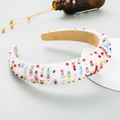 Detail of wide white headband with multicolored crystals on a neutral display stand - AB White
