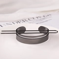 Macro view of a black metal feather hair pin and circular bun holder on a white plate - Minimalist Hoop / Gunmetal