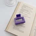 Chic purple medium square claw clip for women displayed on an open vintage book - Deep Purple