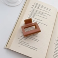 Brown rectangular hair claw clip made of smooth resin placed on an open vintage book - Brown