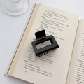 Minimalist black square hair claw clip in glossy resin finish on vintage book background - Pure Black