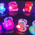 Luminous Christmas rings with Santa and Snowman designs glowing on a dark surface - Christmas Soft Glue LED Ring