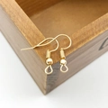 Nahaufnahme goldener DIY-Ohrhaken mit Perlen an einer Vintage-Holzbox-Kante - 100 Stk/Packung / KC Gold