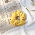 Elegant bright yellow velvet scrunchie placed on newspaper for a stylish hair accessory - Bright Yellow