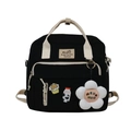 Detail eines schwarzen Canvas-Rucksacks mit cremefarbenen Griffen und niedlichen Bären-Anhängern - Schwarz