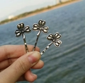 Macro shot of three vintage silver clover hair pins with wavy clips held over water - Antique Silver Clover