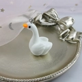 Detailed view of a white resin swan pendant with a metal ring on a vintage gold tray - Swan