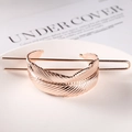 Detail view of a rose gold feather-shaped hair pin with metal texture on a white tray - Feather / Rose Gold
