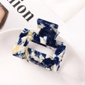 Detail of a square hollow blue marble acetate hair claw clip on a white plate - 7145-10 Blue Marble