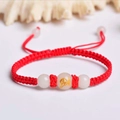 Close-up of handmade red woven bracelet with a luminous bead and golden zodiac patterns - Red Rope [Horse]