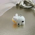 Macro detail of a resin cow charm with a silver metal loop for DIY jewelry making - Cow