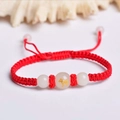 Macro detail of red woven bracelet with jade beads and golden ox zodiac engraving - Red Rope [Ox]