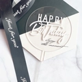 Clear acrylic round Happy Birthday cake topper with white lettering on marble surface - Acrylic / White