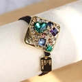 Golden baroque hair tie featuring a large green heart crystal and colorful rhinestones - Square Style