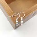 Silver DIY earring hooks with bead and coil detail displayed on a wooden edge - 100 Pcs/Pack / Bright Silver