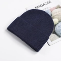 Navy blue winter knit beanie with ribbed texture and folded cuff displayed on a magazine - Navy Blue
