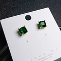 Macro detail of cushion-cut green gemstone studs with 925 silver posts on a display card - Green and Gold